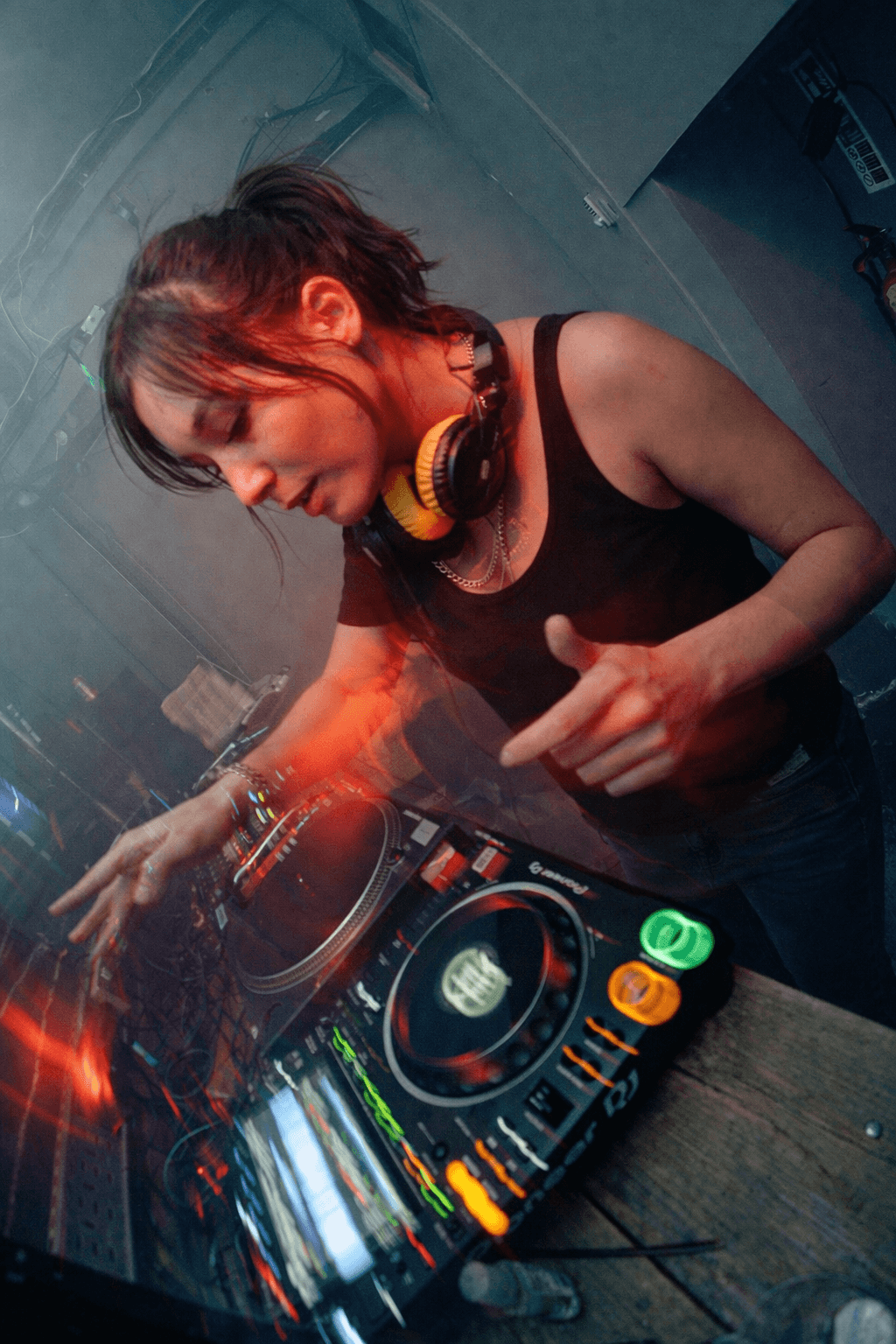Woman DJing in a low-lit venue.