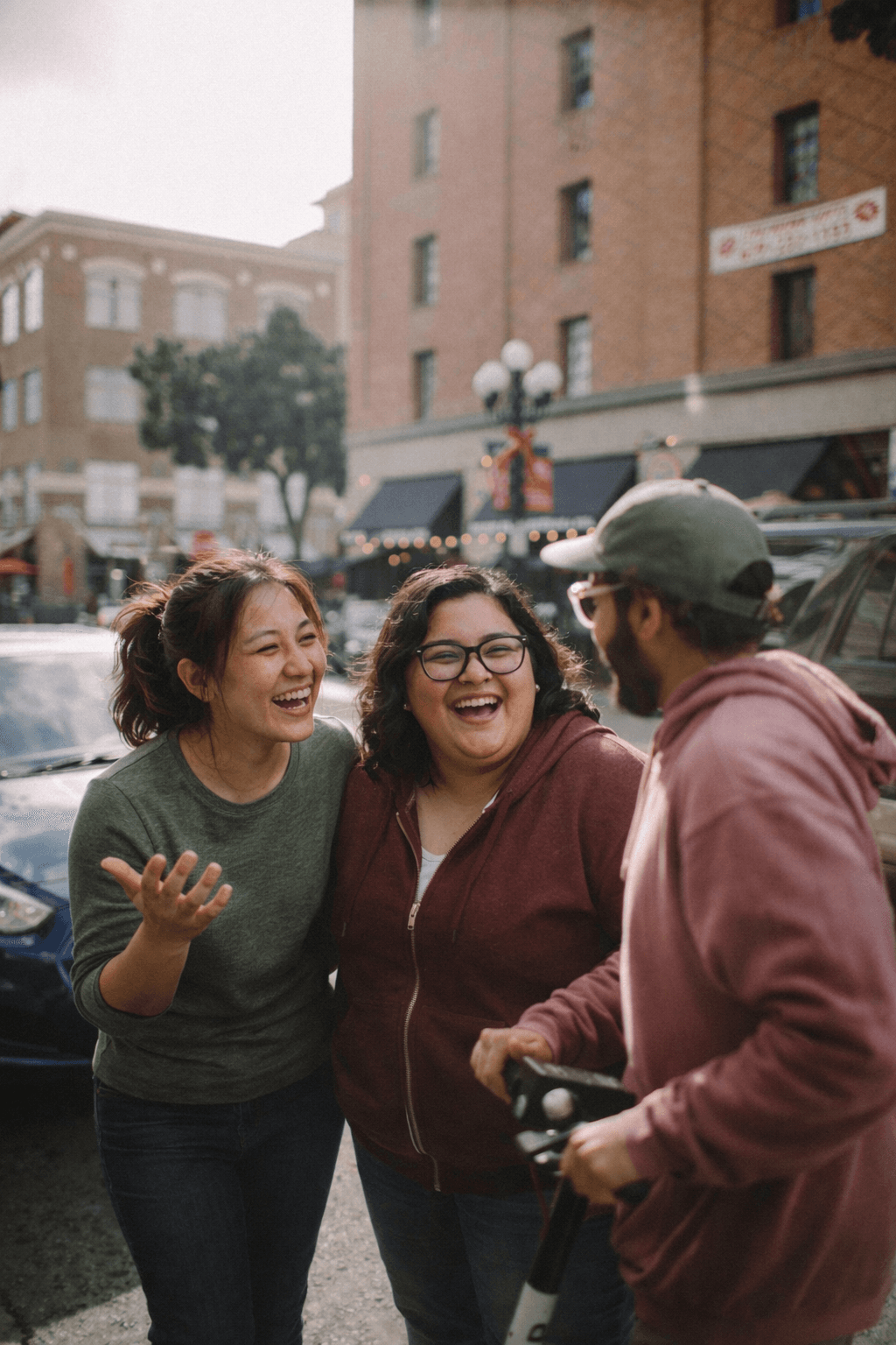 Three friends laughing together in a city street.